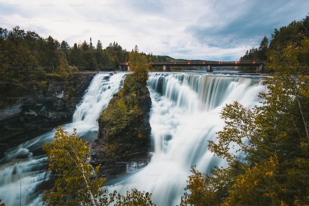 a large waterfall with a bridge over it