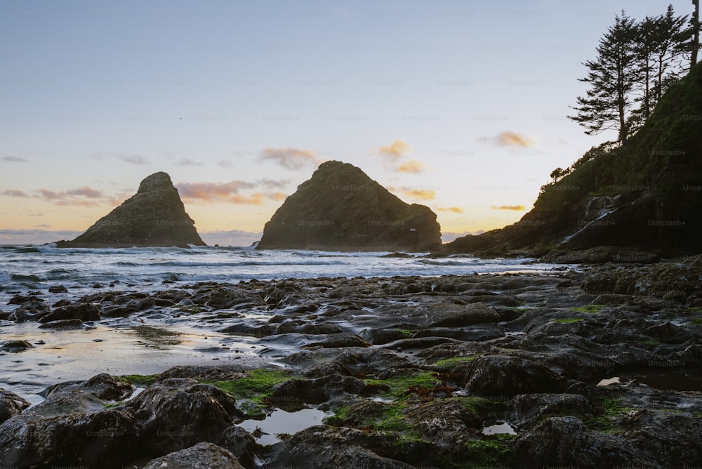 a rocky beach with a couple of large rocks in the background