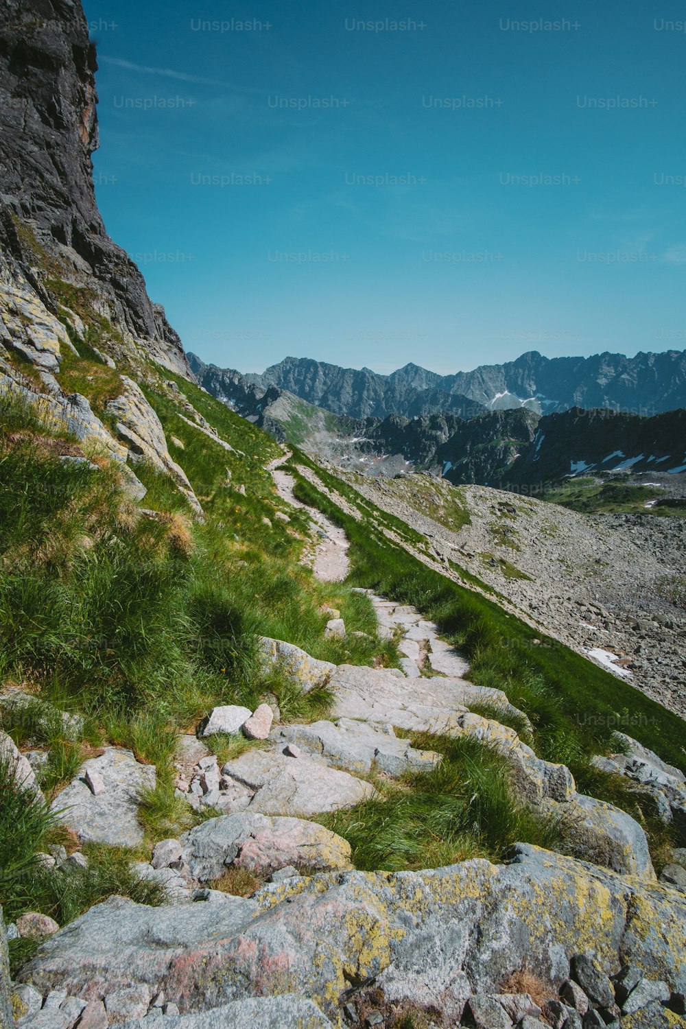 a rocky trail with grass and rocks on the side