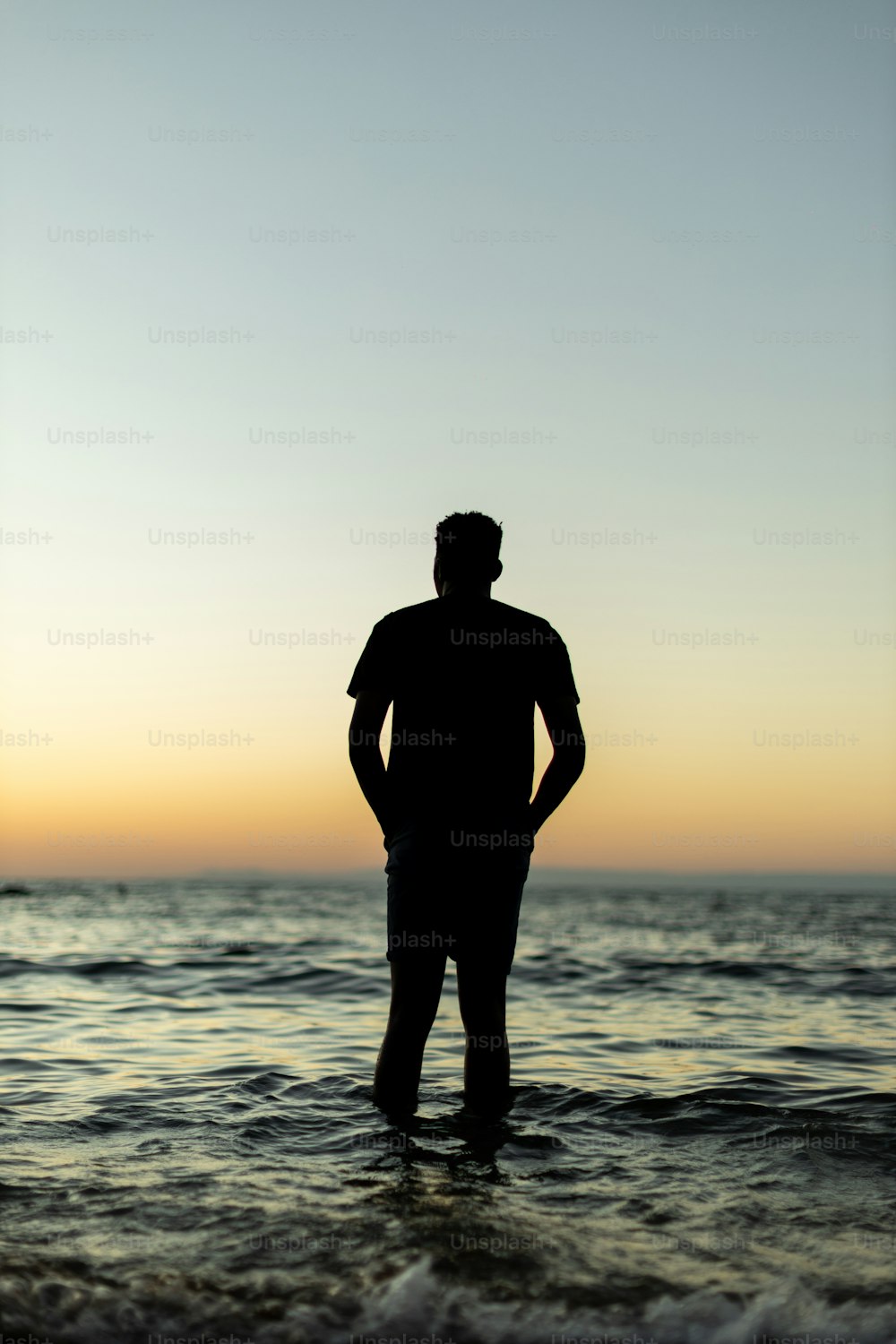 a man standing in the ocean at sunset