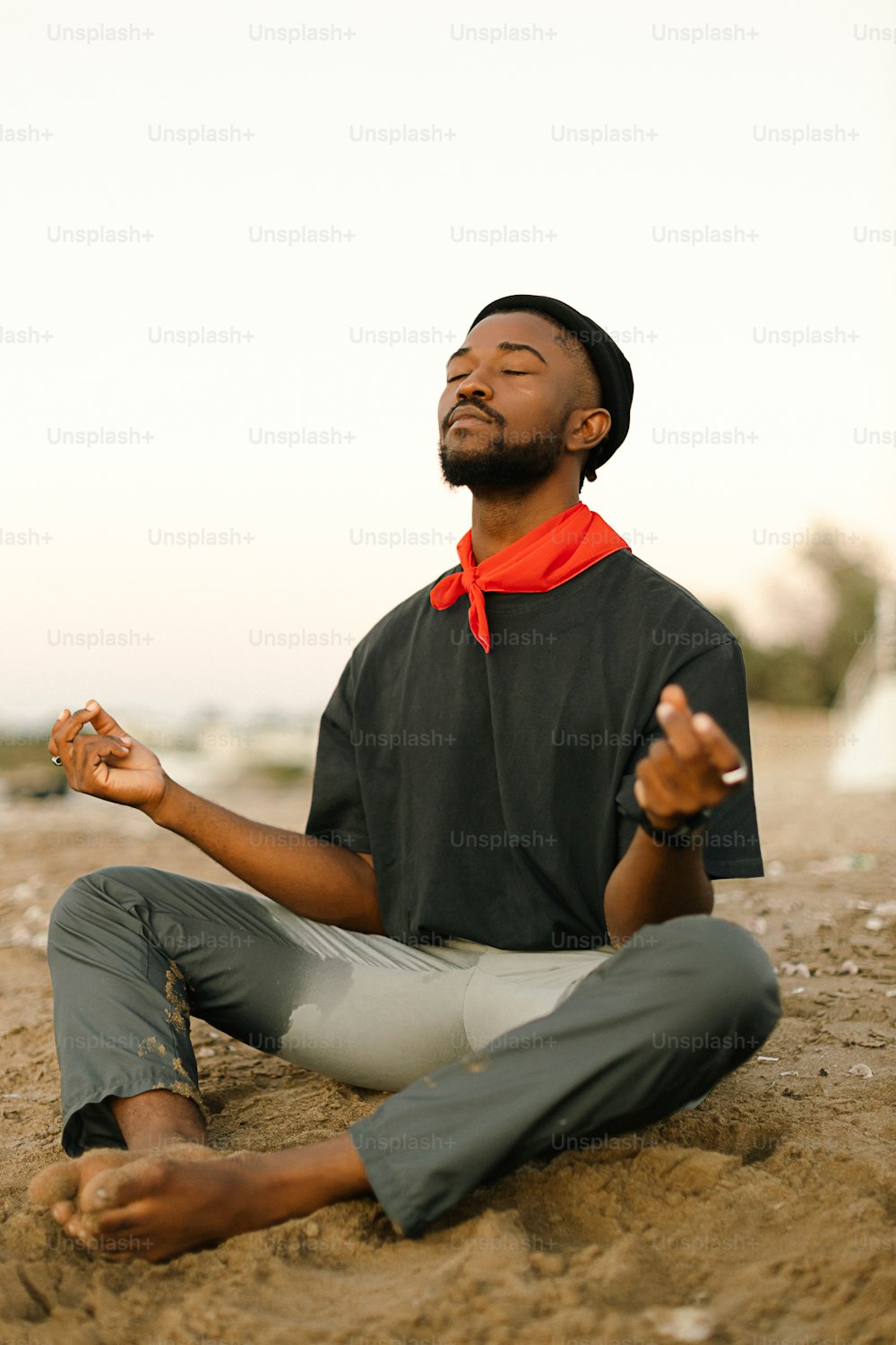 a man sitting in the sand with his eyes closed