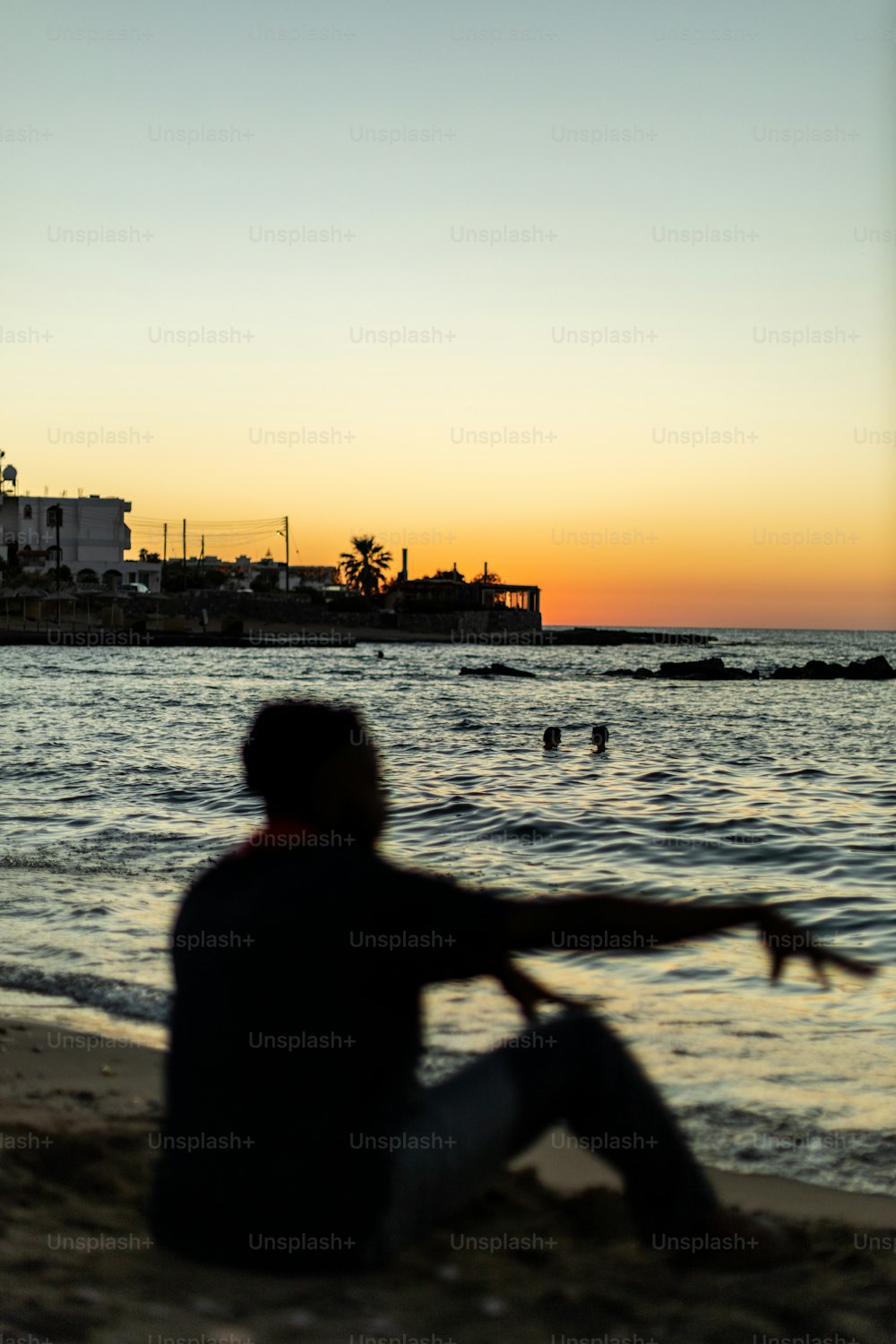 a man sitting on the beach watching the sunset