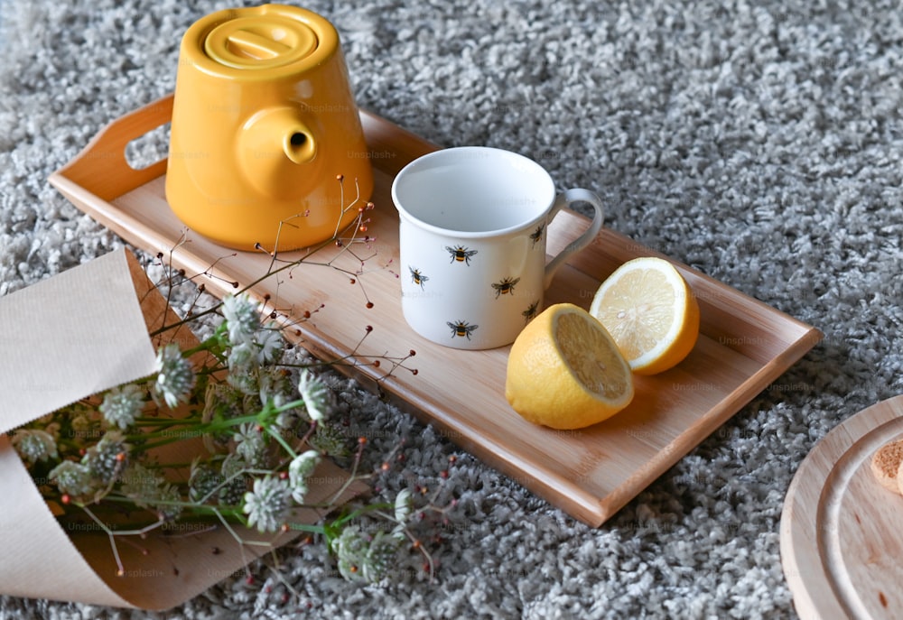 a tray with a teapot, lemon and a cup on it