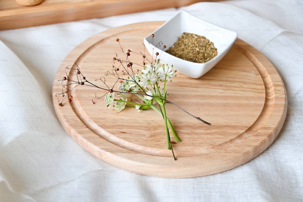 a wooden tray with a flower and a small bowl on it