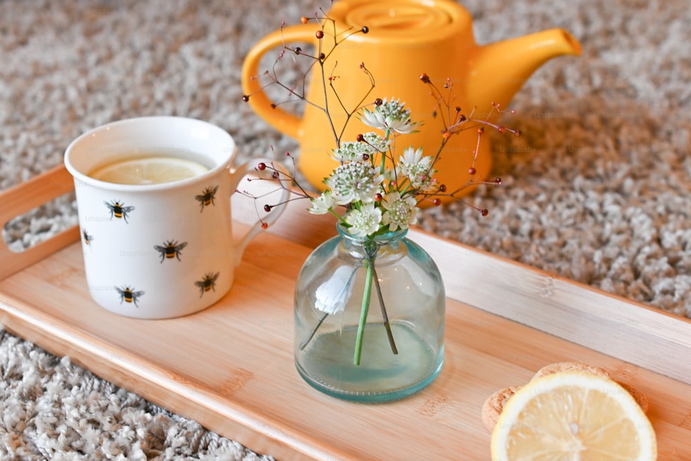una bandeja con un jarrón de flores y una taza de té
