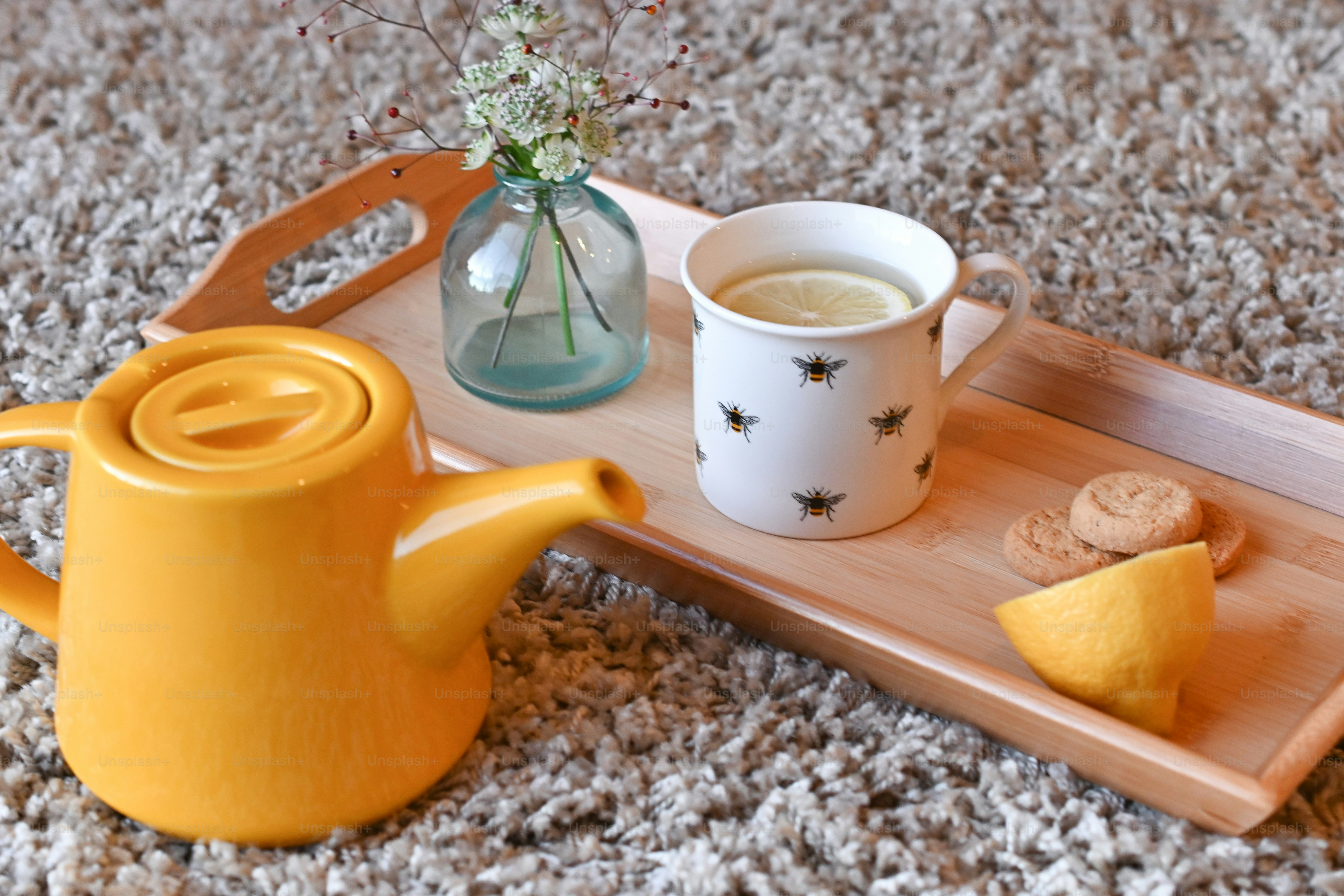 a tray with a cup of tea, cookies and a vase of flowers
