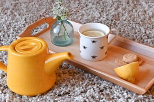 uma bandeja com uma xícara de chá, biscoitos e um vaso de flores