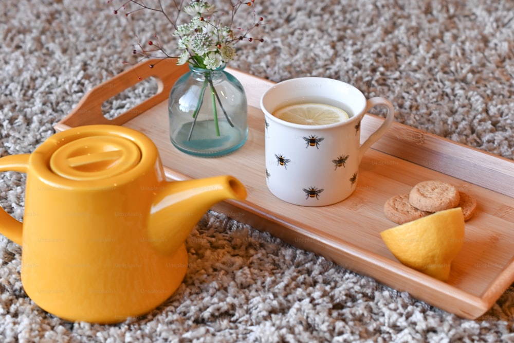 a tray with a cup of tea, cookies and a vase of flowers