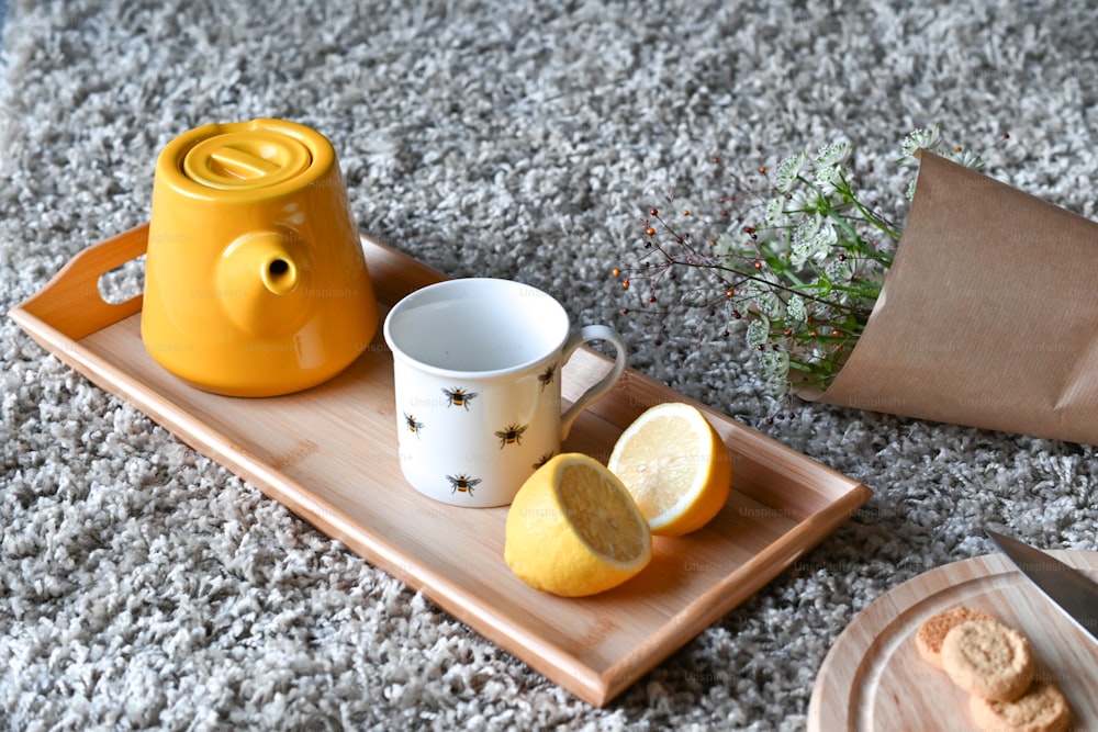 a tray with a tea pot, a cup of tea and a slice of lemon