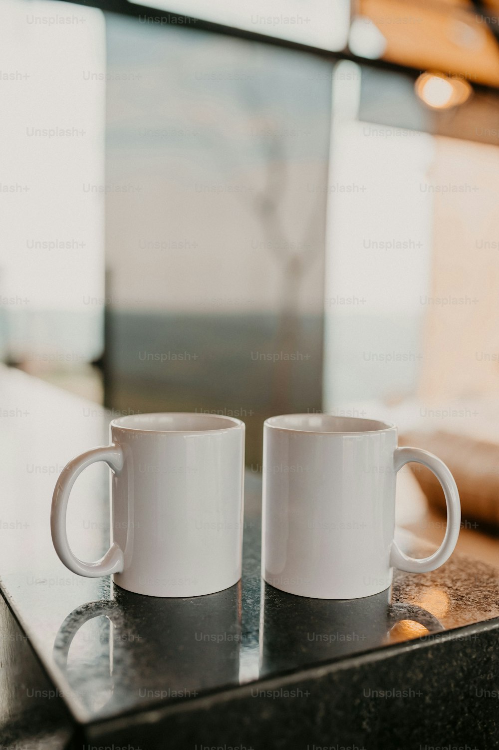 Dos tazas de café blancas sentadas encima de un mostrador