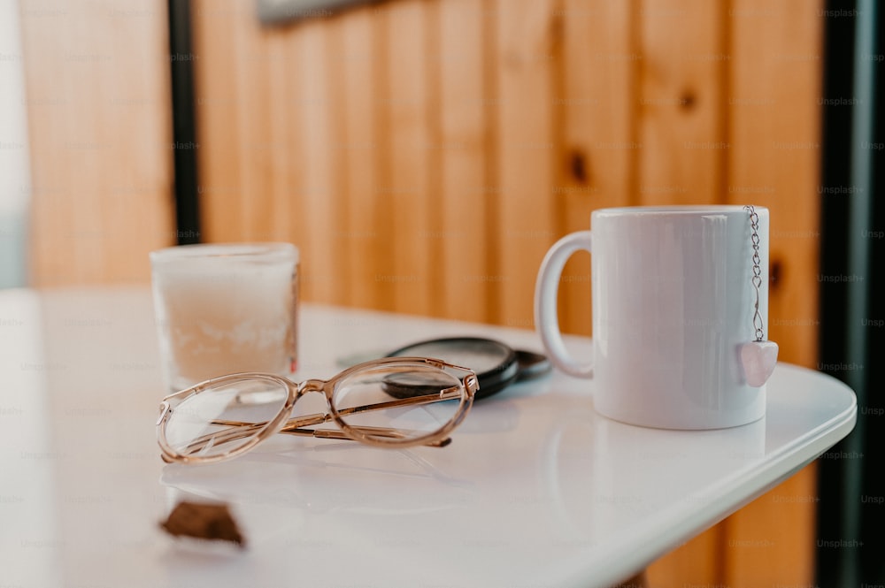 a pair of glasses sitting on top of a table next to a cup