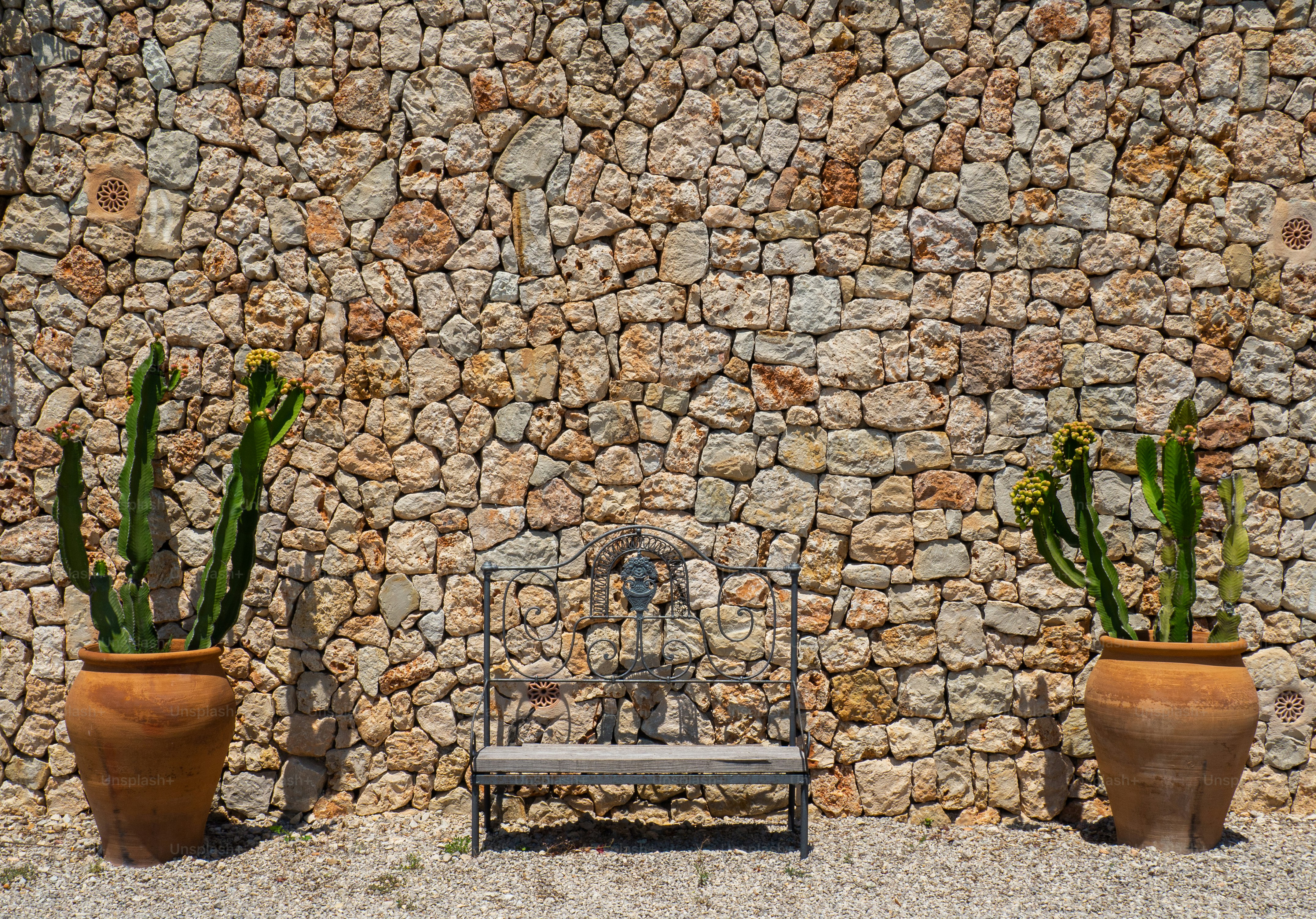 a bench sitting next to two large potted plants