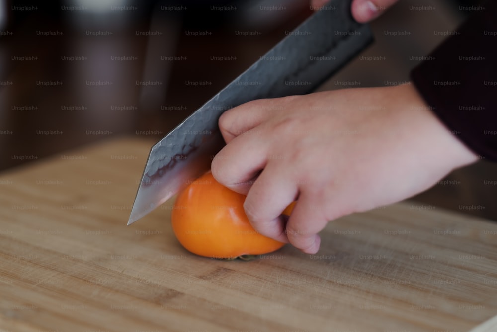 Eine Person schneidet eine Orange mit einem Messer