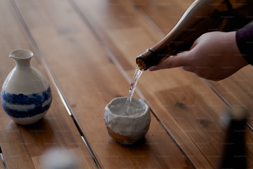 a person pours a bottle of wine into a small bowl