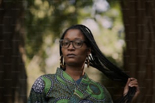 a woman with glasses and braids standing in a forest