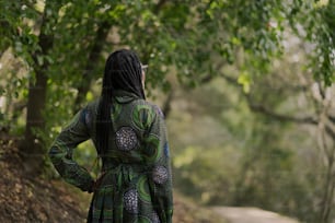 a woman in a green dress standing on a dirt road