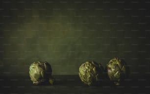 three artichokes sitting on a table in a dark room