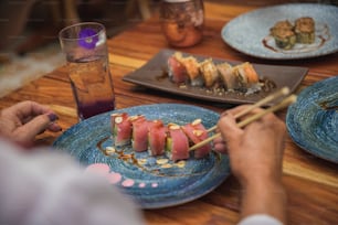 une personne mangeant des sushis sur une assiette bleue