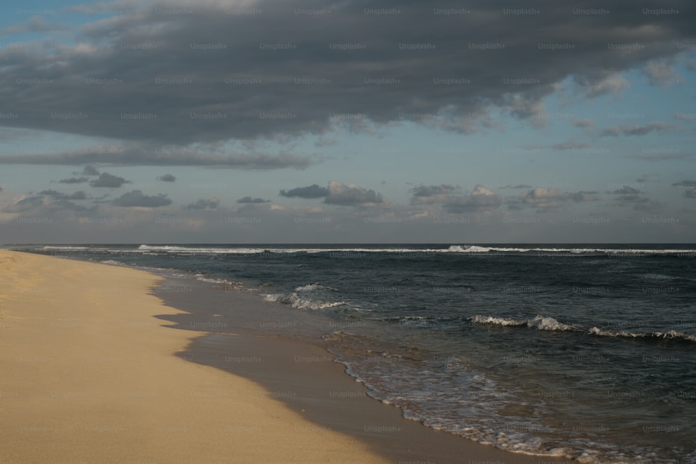 a sandy beach with waves coming in to shore