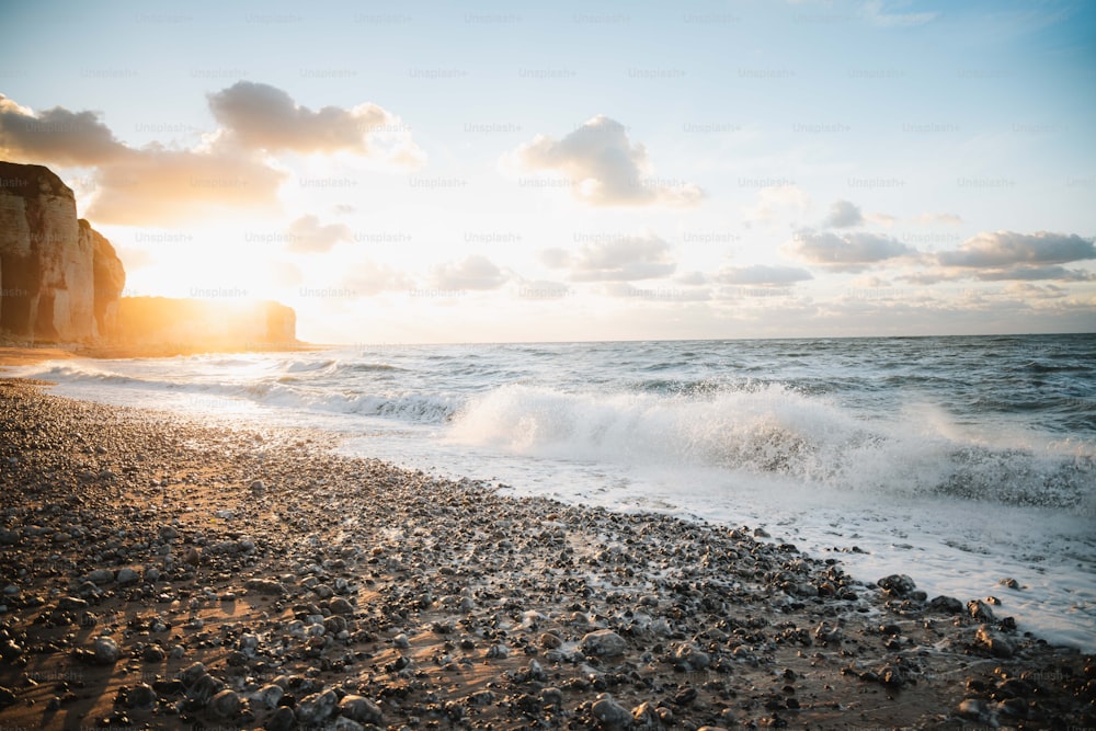 the sun is setting over a rocky beach