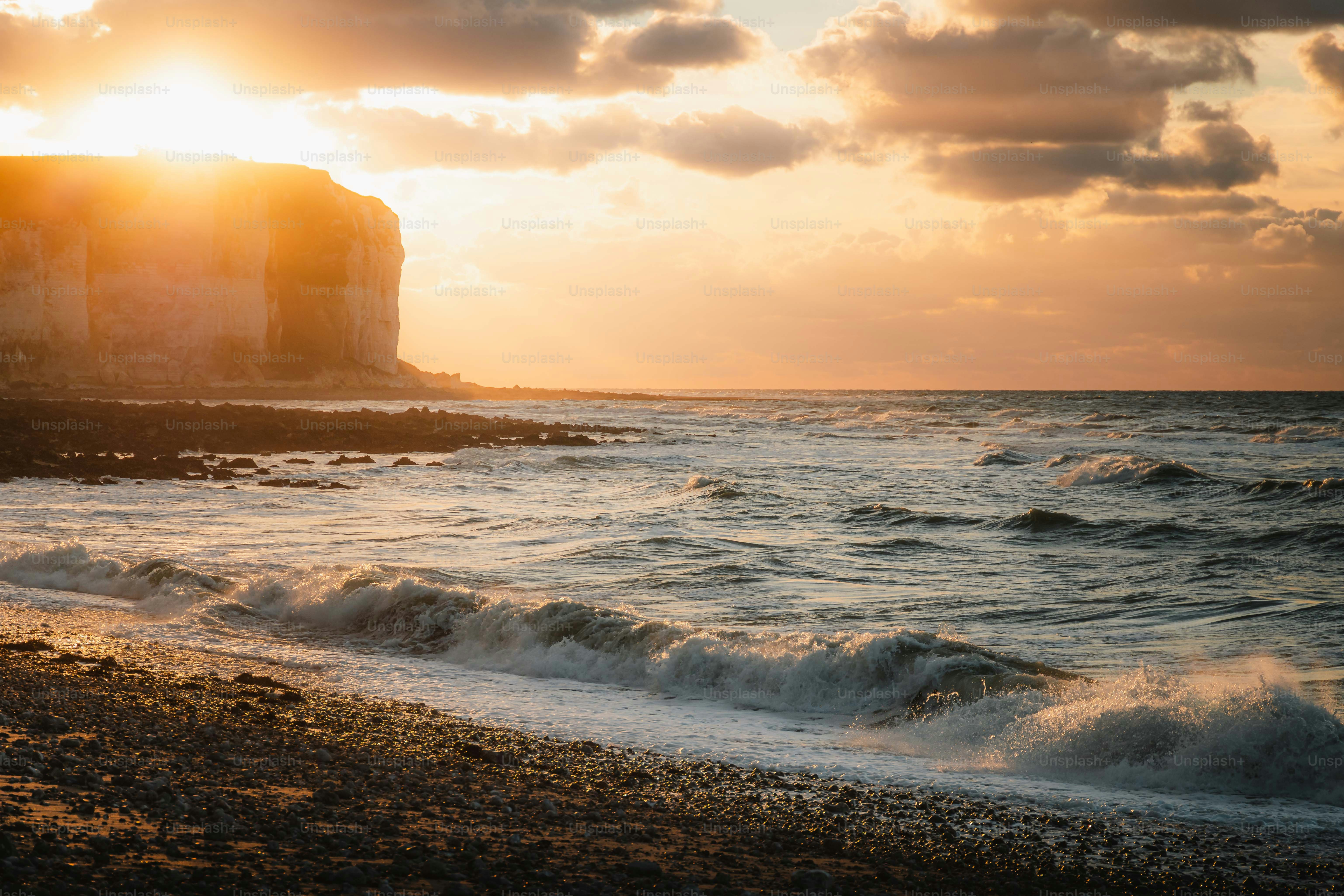 the sun is setting over the water at the beach
