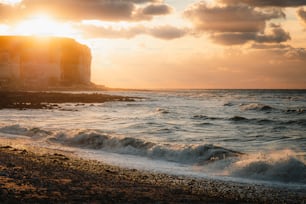 the sun is setting over the water at the beach