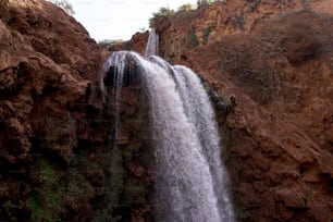 a very tall waterfall in the middle of a rocky area