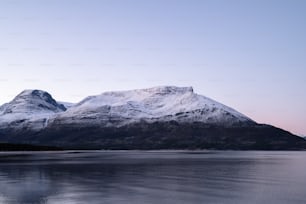 a mountain covered in snow next to a body of water