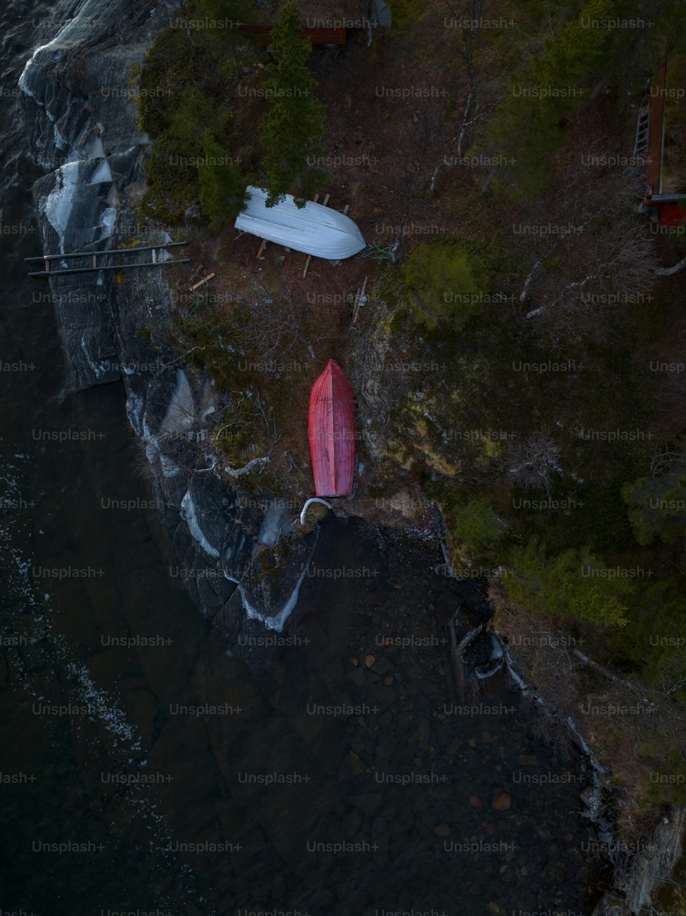 Una tabla de surf roja sentada en la cima de un acantilado junto a un cuerpo de agua