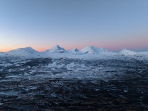 a view of a snowy mountain range at sunset