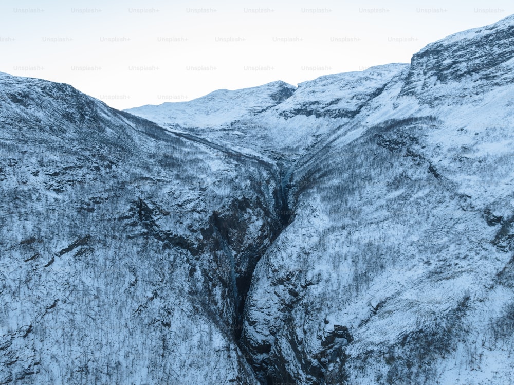 a snowy mountain with a stream running through it