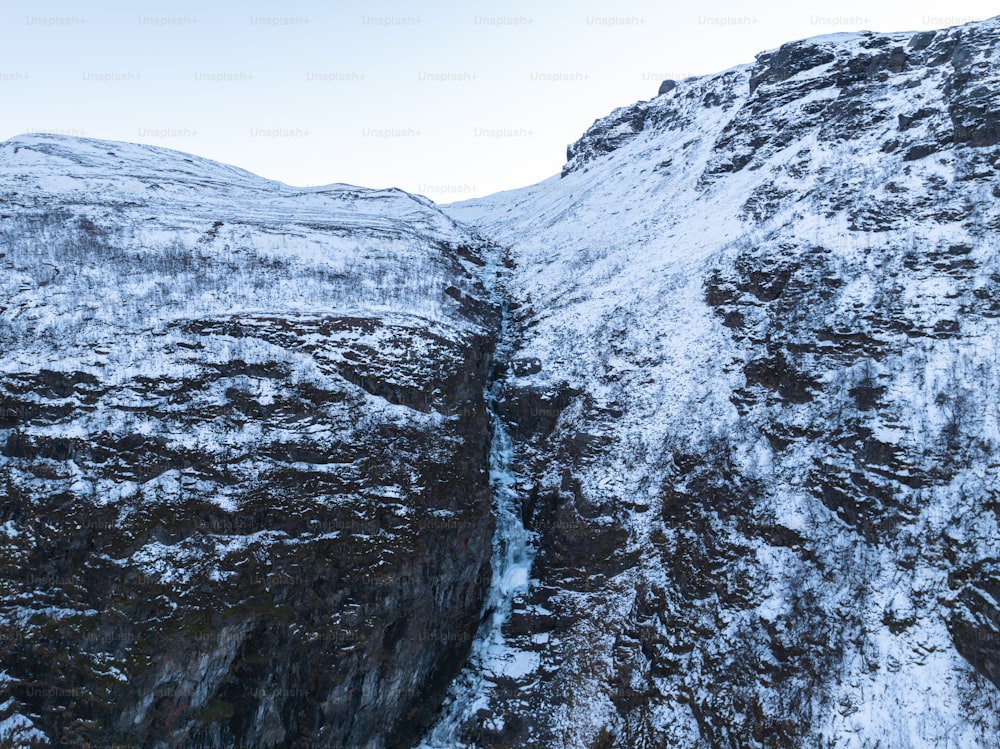a snow covered mountain side with a small waterfall