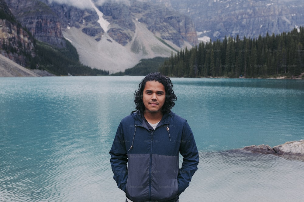 a man standing in front of a mountain lake