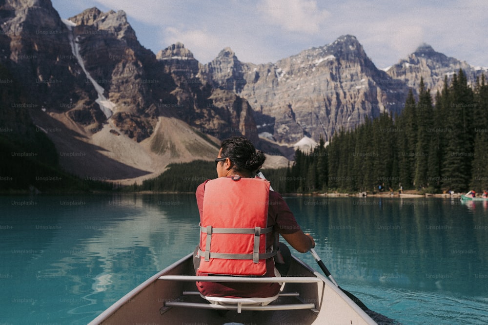 a person in a boat on a lake with mountains in the background