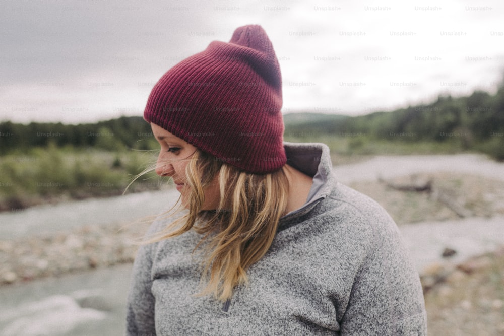 a woman wearing a red hat standing next to a river