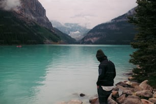 Ein Mann, der an einem felsigen Ufer neben einem Gewässer steht