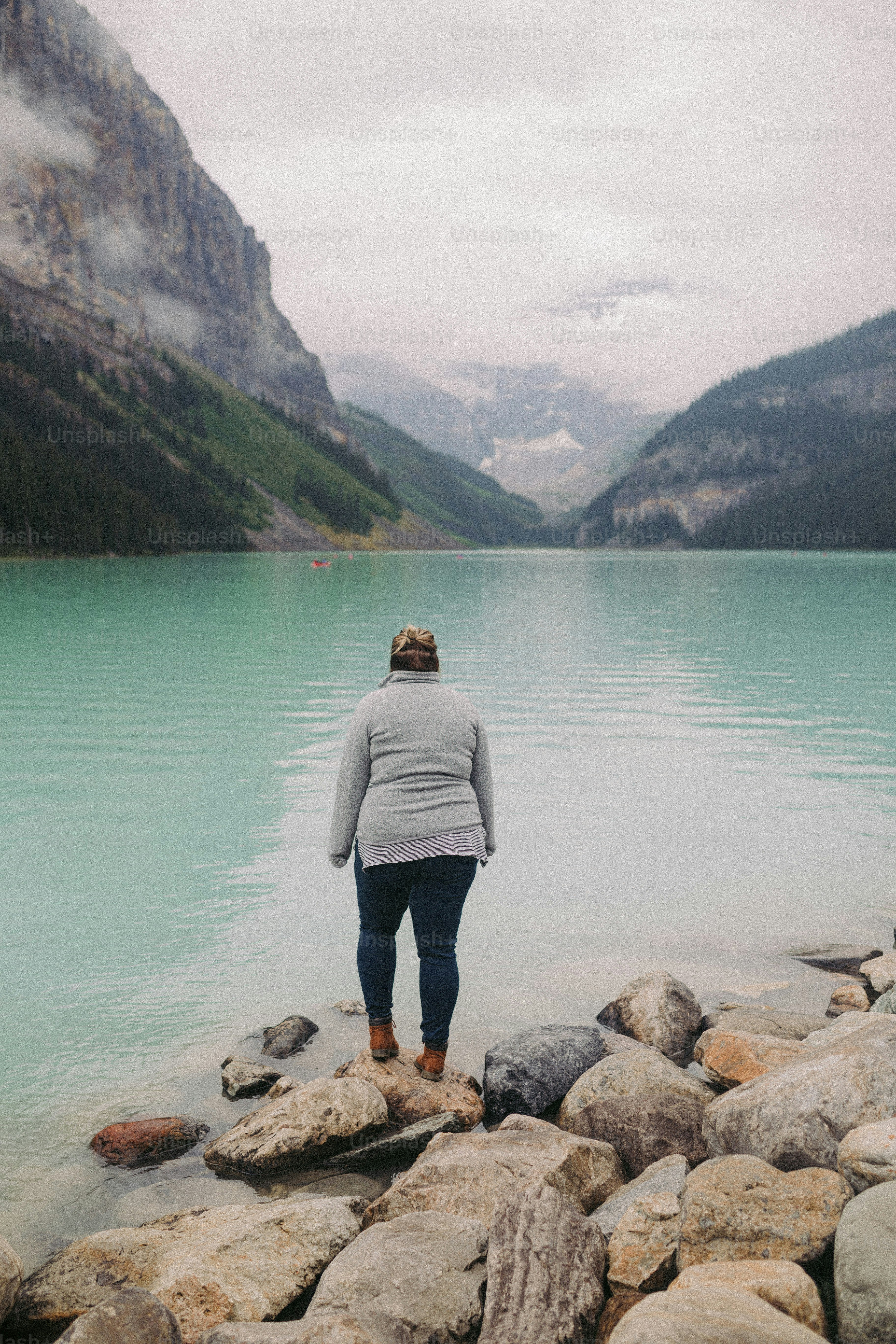 a woman standing on rocks near a body of water