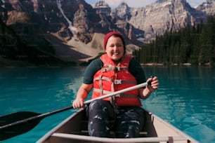 a woman in a red life jacket paddling a canoe