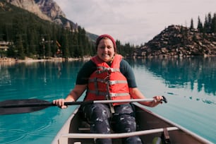 Una mujer con un chaleco salvavidas rojo remando en una canoa