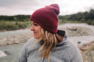 a woman wearing a red hat standing next to a river