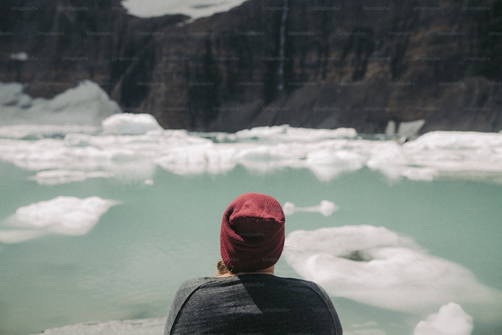 a person wearing a red hat looking at icebergs