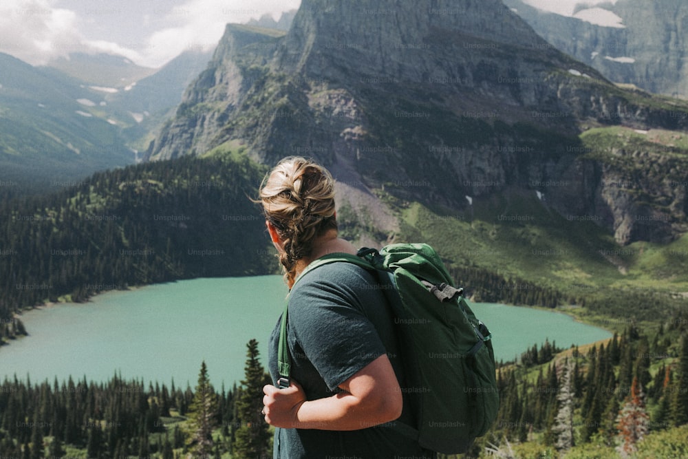 a person with a backpack looking at a mountain lake
