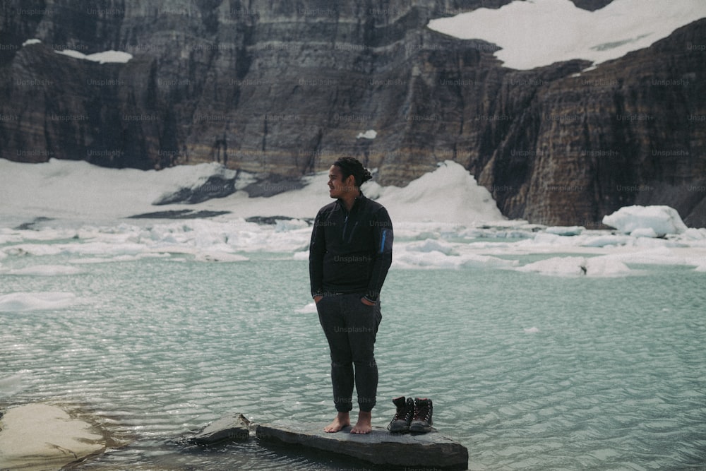 um homem em pé sobre uma rocha no meio de um lago
