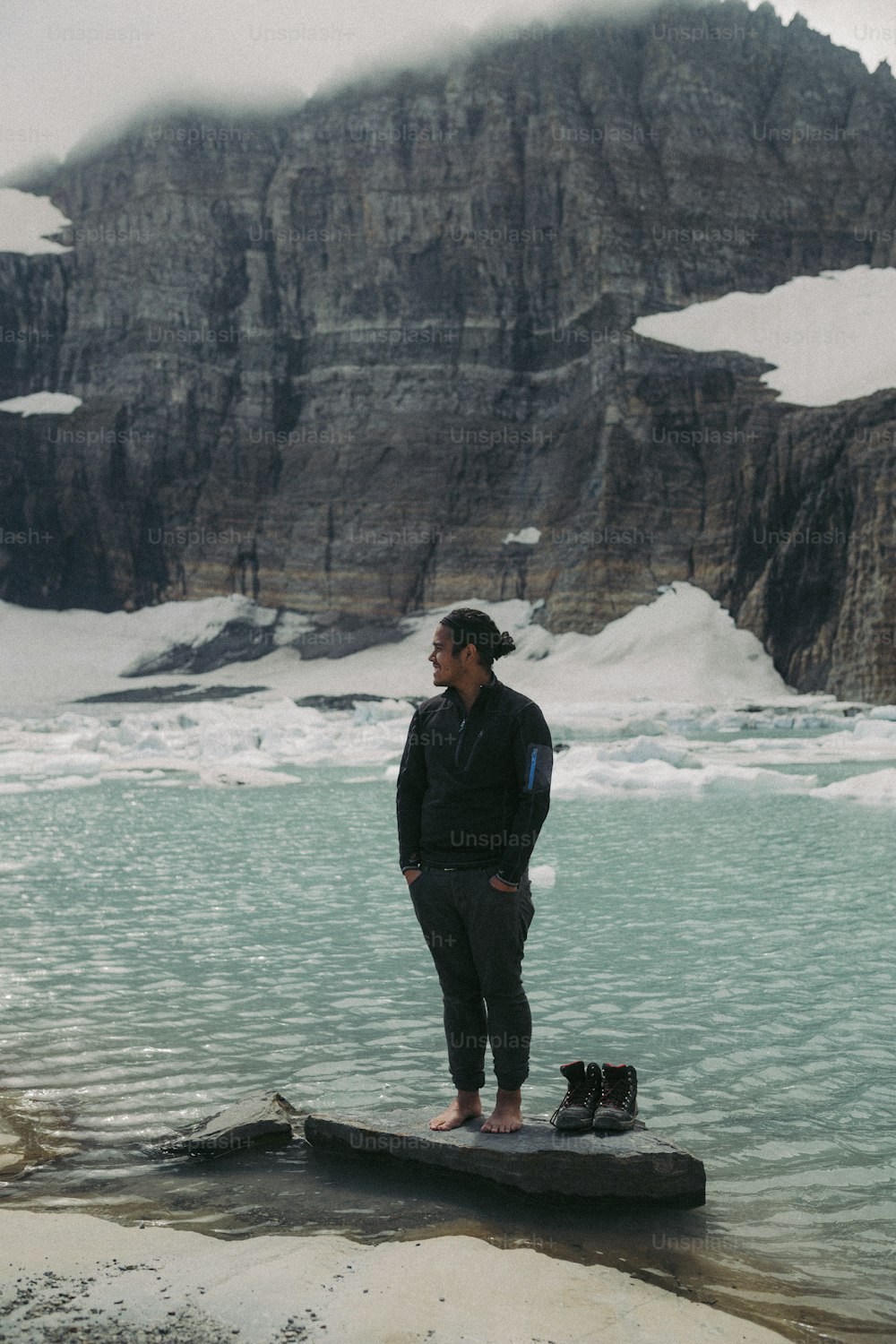 Un uomo in piedi su una roccia di fronte a uno specchio d'acqua