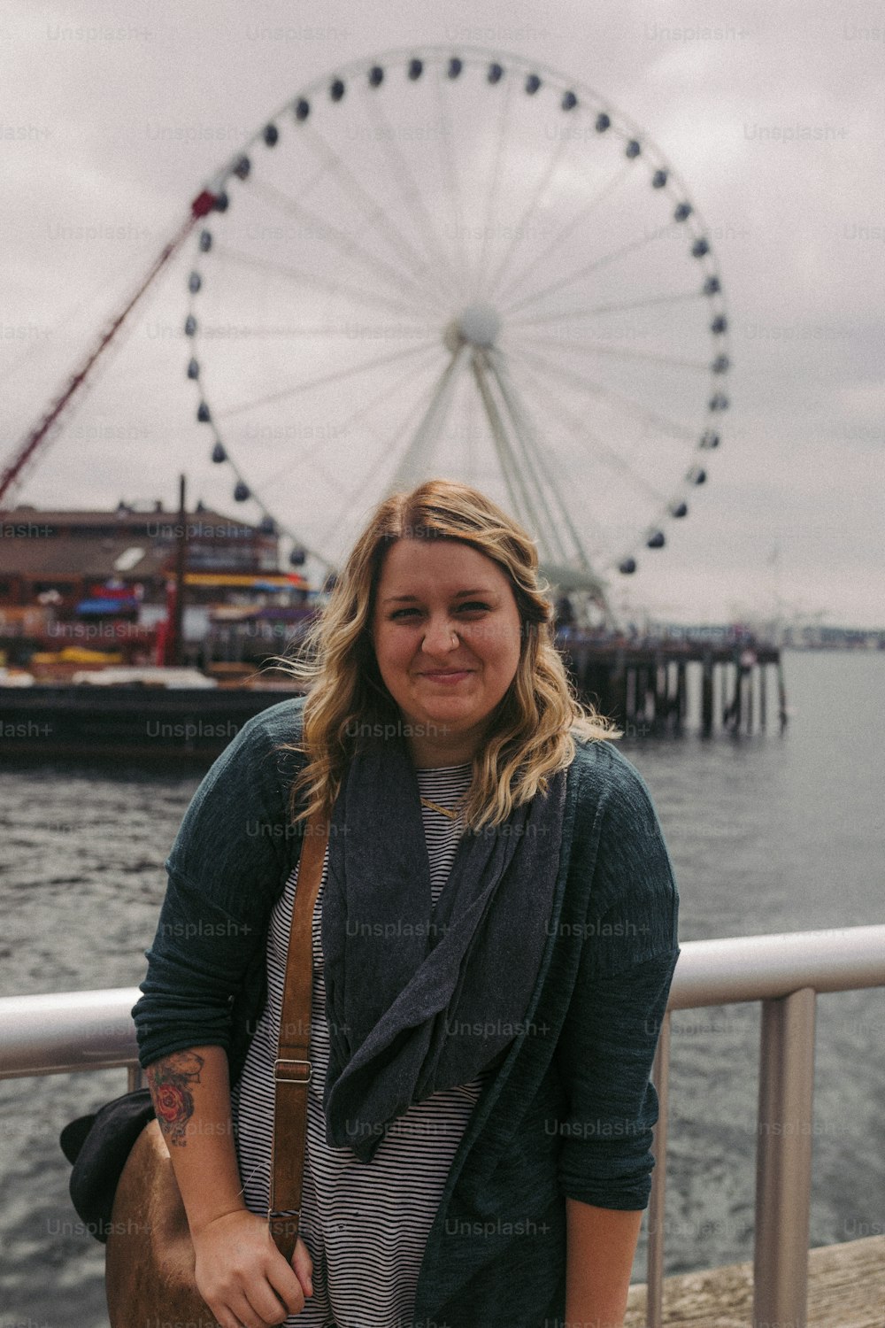 a woman standing on a pier next to a ferris wheel