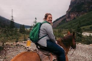 a woman is riding a horse in the mountains
