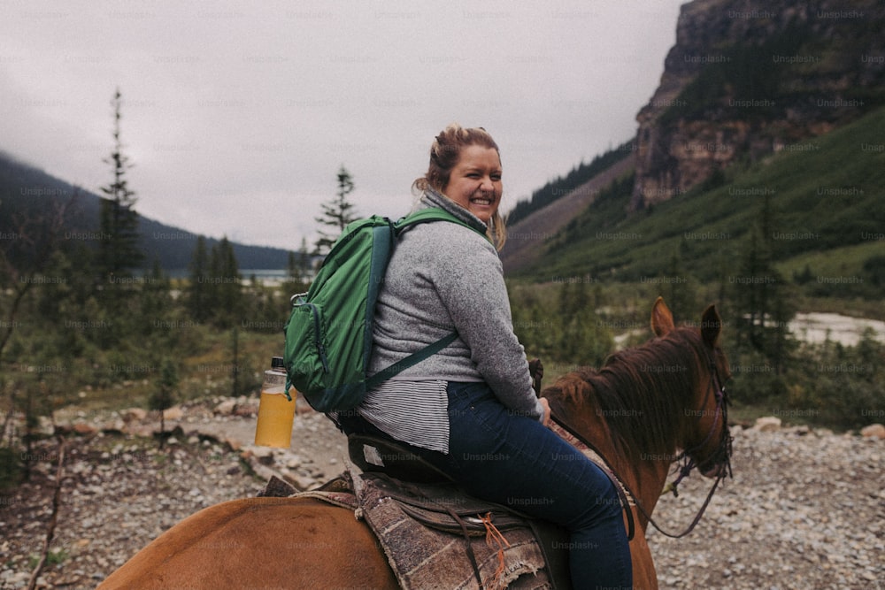 a woman is riding a horse in the mountains