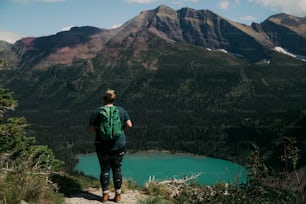 Una persona in piedi su una montagna che guarda un lago
