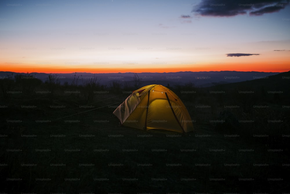 a yellow tent sitting on top of a lush green field