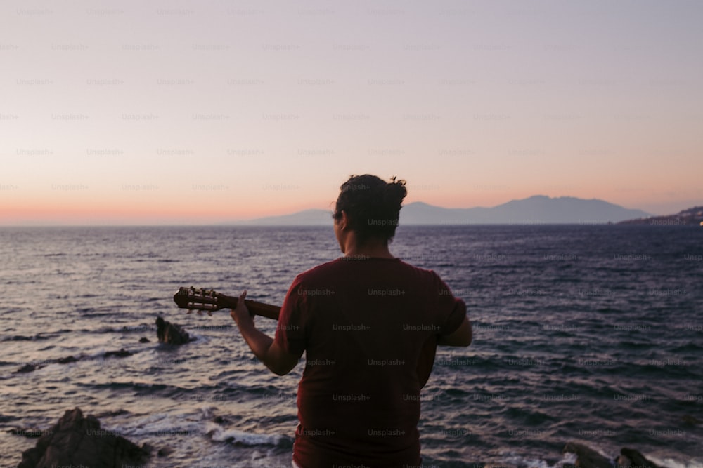 a man playing a guitar on the beach